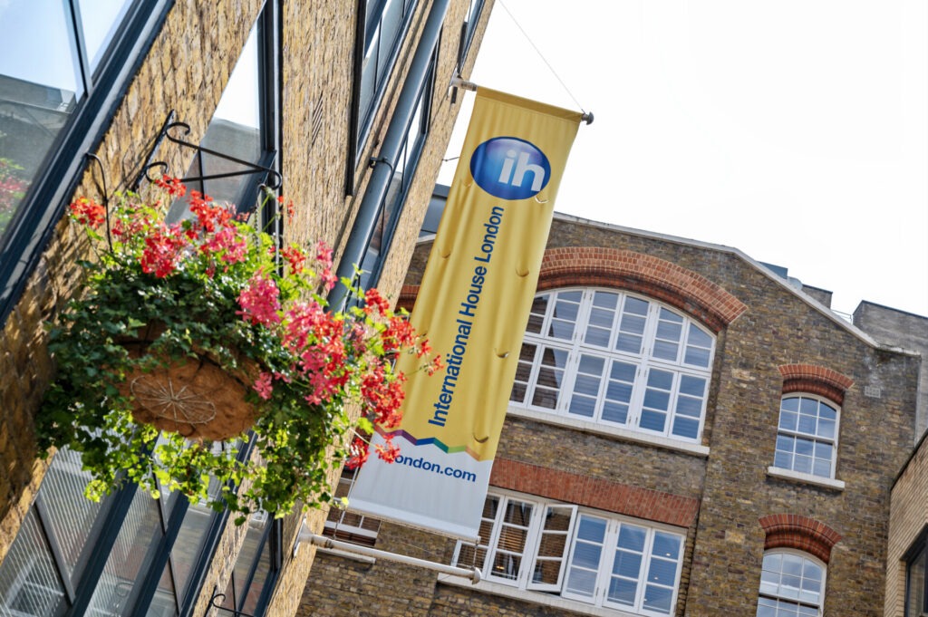 Fassade des International House London mit Banner und Blumen.
