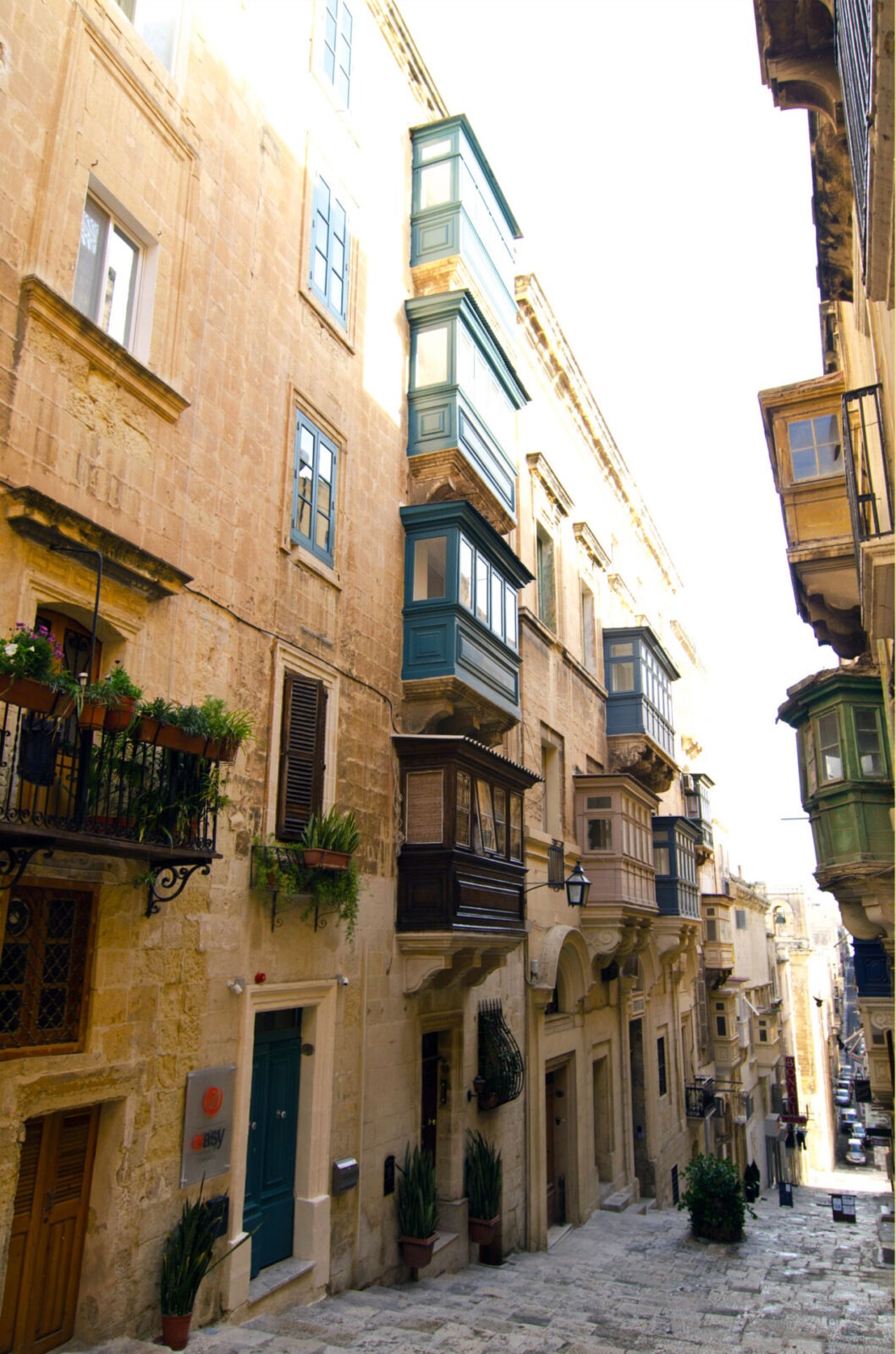 Historische Straße in Valletta, Malta, mit traditionellen maltesischen Holzbalkonen und Sandsteingebäuden.