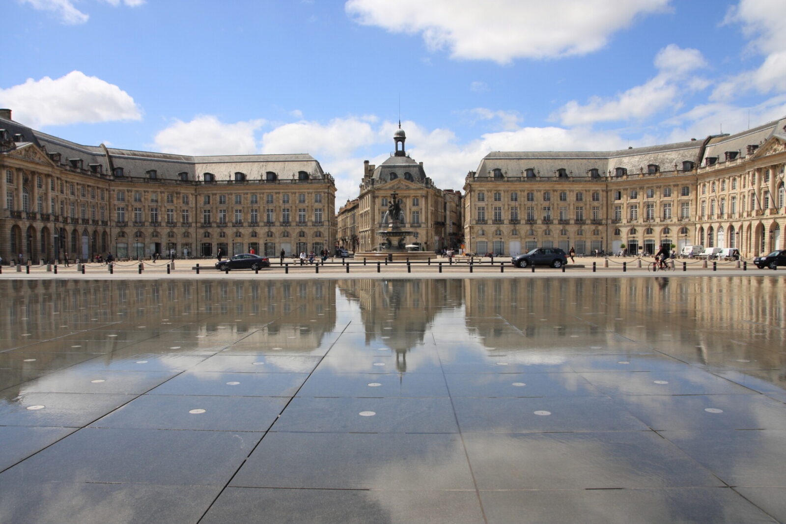 Place de la Bourse in Bordeaux mit der Spiegelung im Miroir d'eau bei blauem Himmel.
