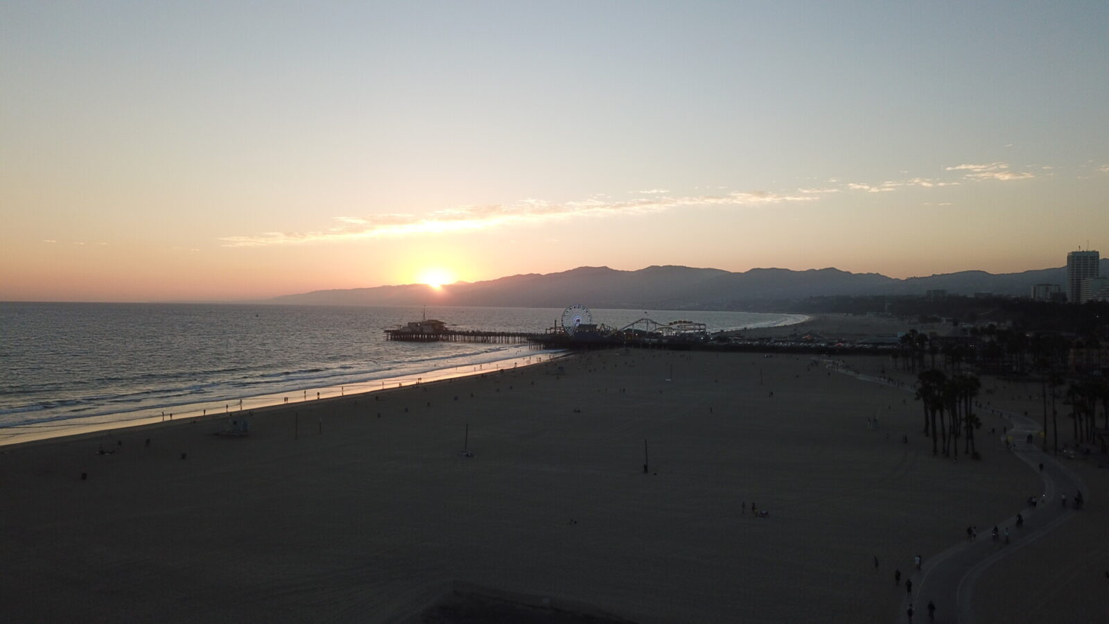 Sonnenuntergang über dem Santa Monica Pier in Los Angeles mit Blick auf den Pazifik und die Küstenberge.