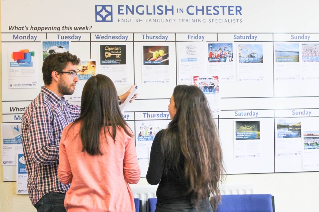 Drei Sprachschüler in der „English in Chester“ Sprachschule besprechen das Wochenprogramm mit verschiedenen Aktivitäten.