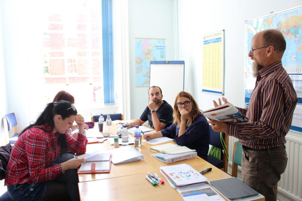 Englischunterricht in einer Sprachschule in Chester mit engagierten Schülern und einem Lehrer, der eine interaktive Lektion hält.