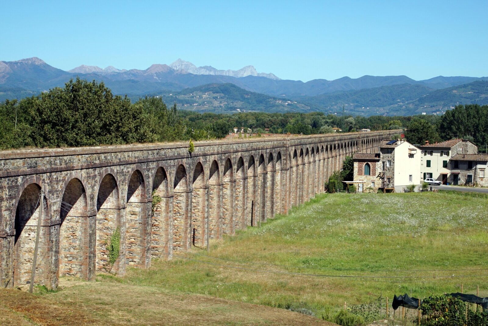Historisches Aquädukt von Lucca in der Toskana, Italien, mit beeindruckenden Steinbögen und einer malerischen Berglandschaft im Hintergrund.