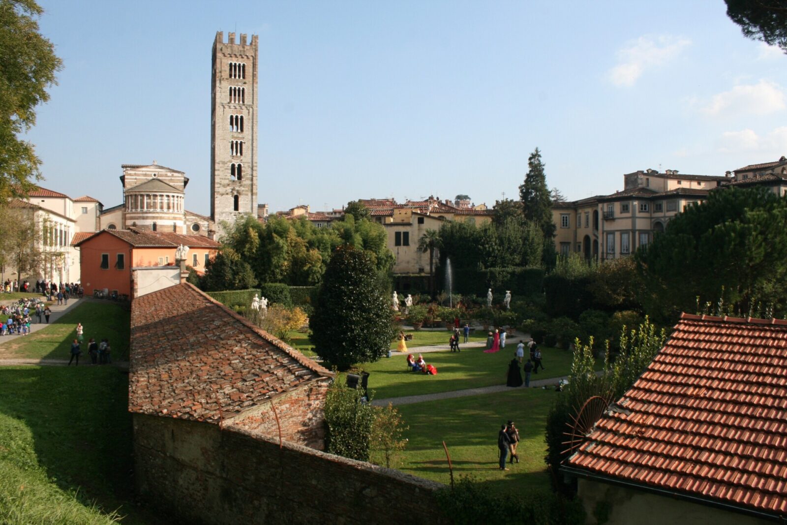 Historischer Garten mit Statuen und Springbrunnen in Lucca, Italien, mit einem markanten Glockenturm im Hintergrund.