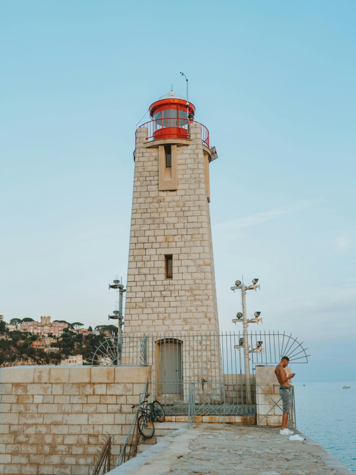 Historischer Leuchtturm am Hafen von Nizza mit Blick auf das Mittelmeer und die Küstenlandschaft.