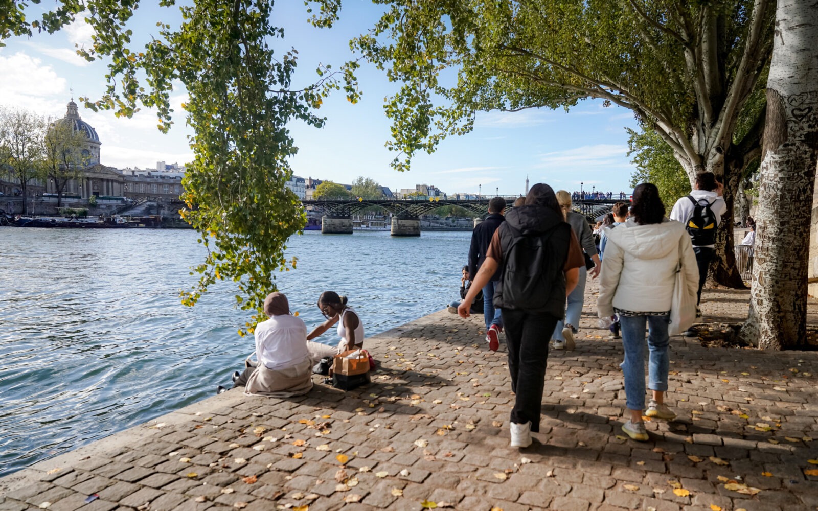 Spaziergänger entlang der Seine in Paris mit Blick auf die Pont des Arts.