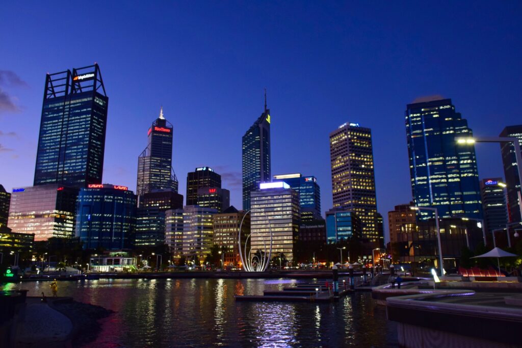 Beleuchtete Skyline von Perth bei Nacht mit Reflexionen auf dem Wasser.