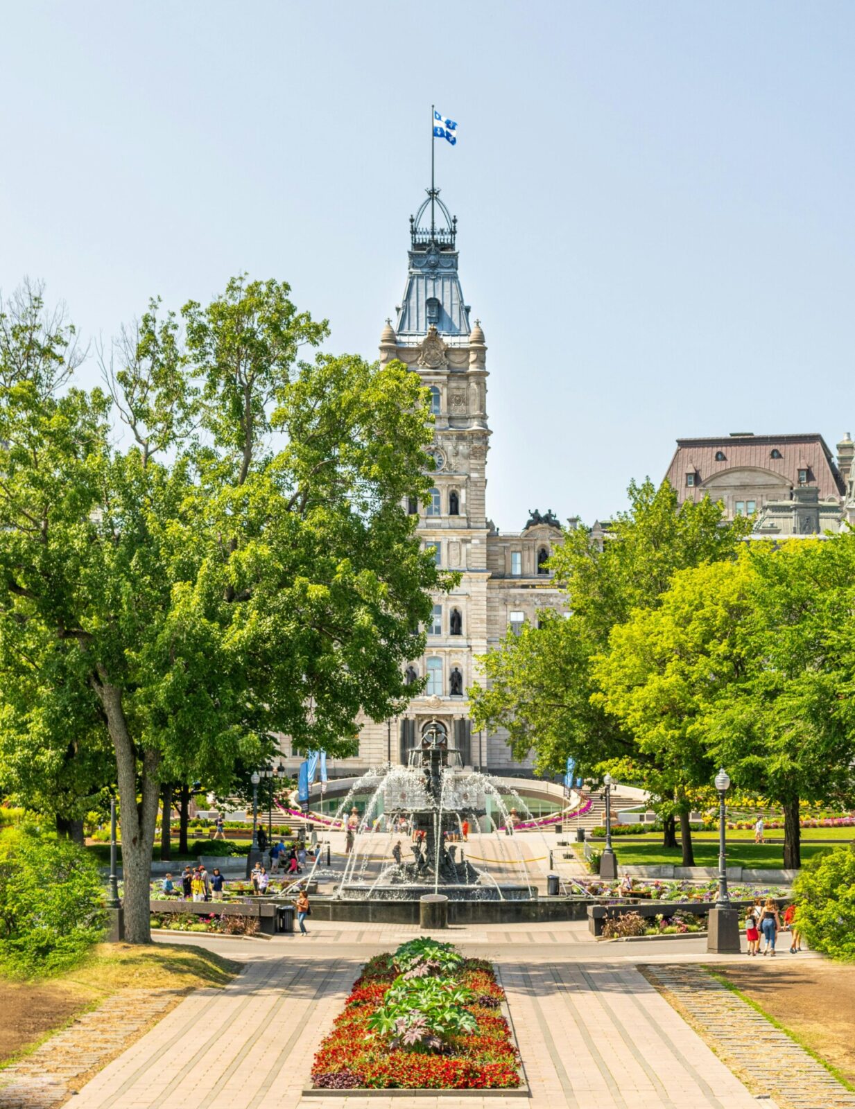 Das Parlamentsgebäude von Québec mit der Fontaine de Tourny und einer blühenden Gartenanlage.