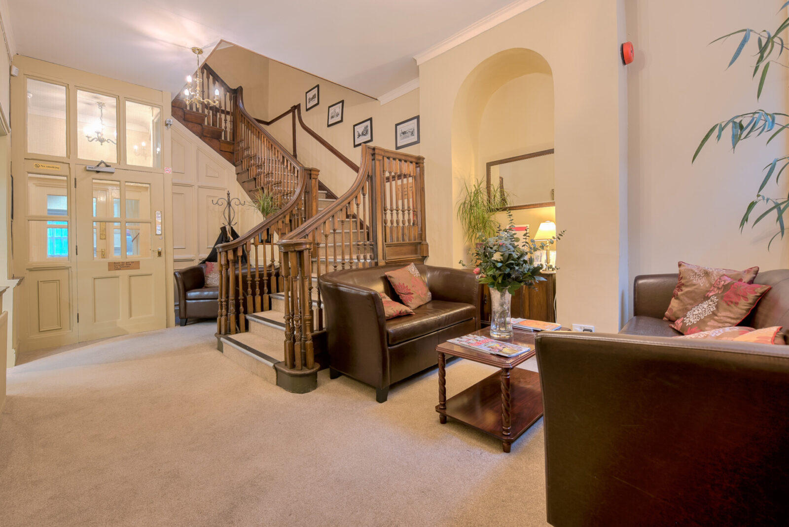 Einladender Empfangsbereich mit gemütlichen Ledersofas und einer stilvollen Holztreppe in der Severnvale Academy.