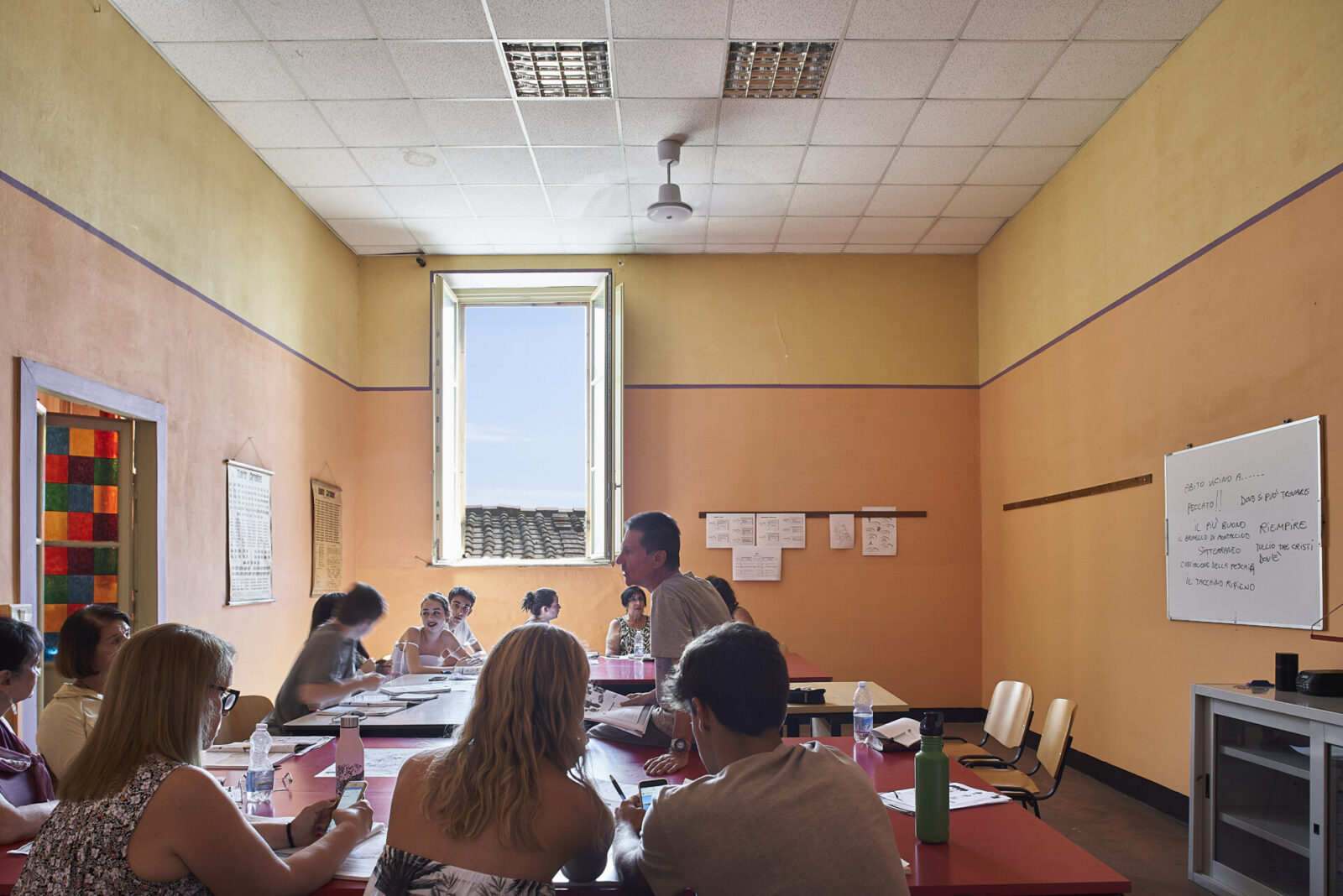Sprachkurs in einem sonnendurchfluteten Klassenzimmer mit Lehrer und internationalen Schülern.
