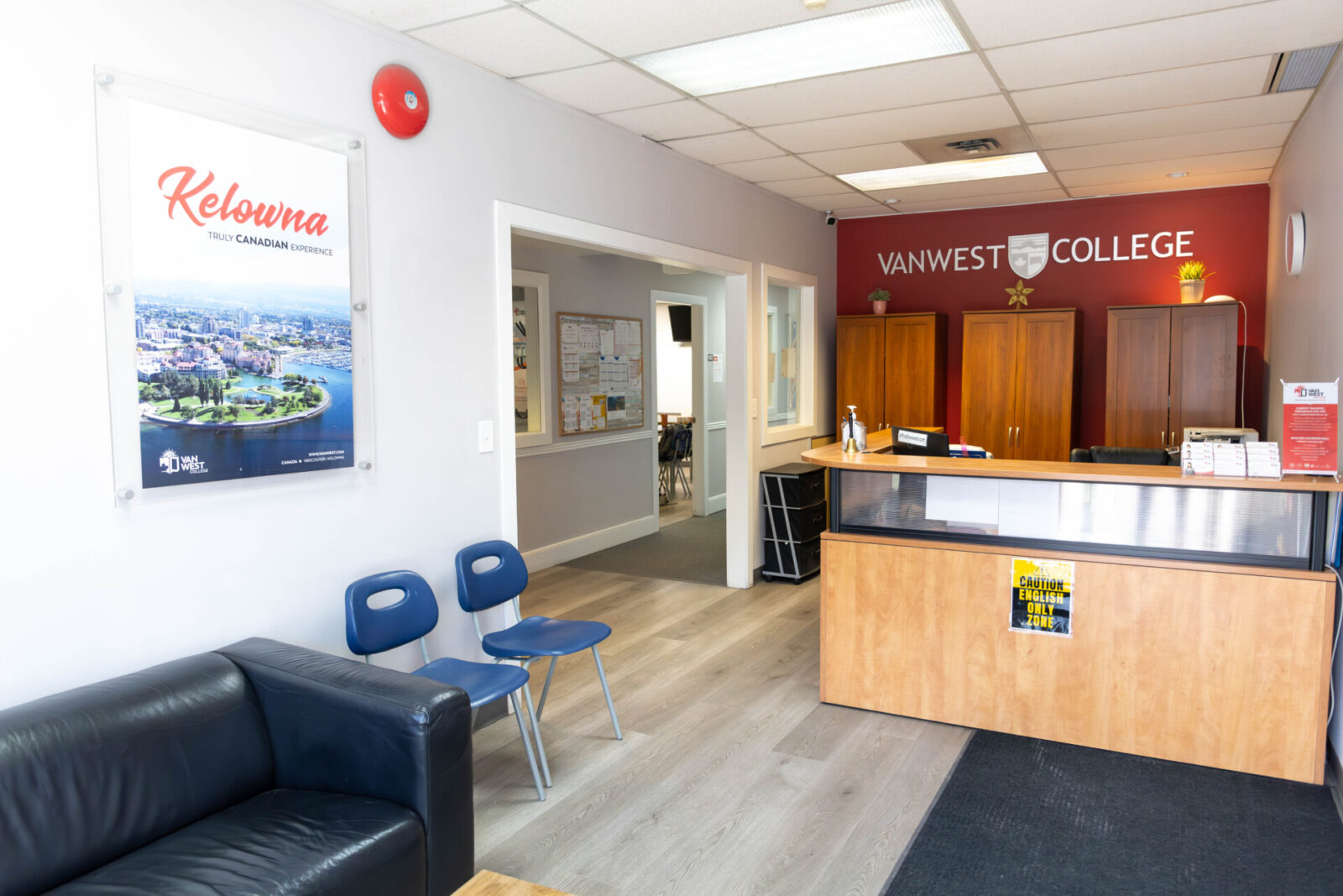 Empfangsbereich des VanWest College mit moderner Einrichtung und Kelowna-Reiseposter.
