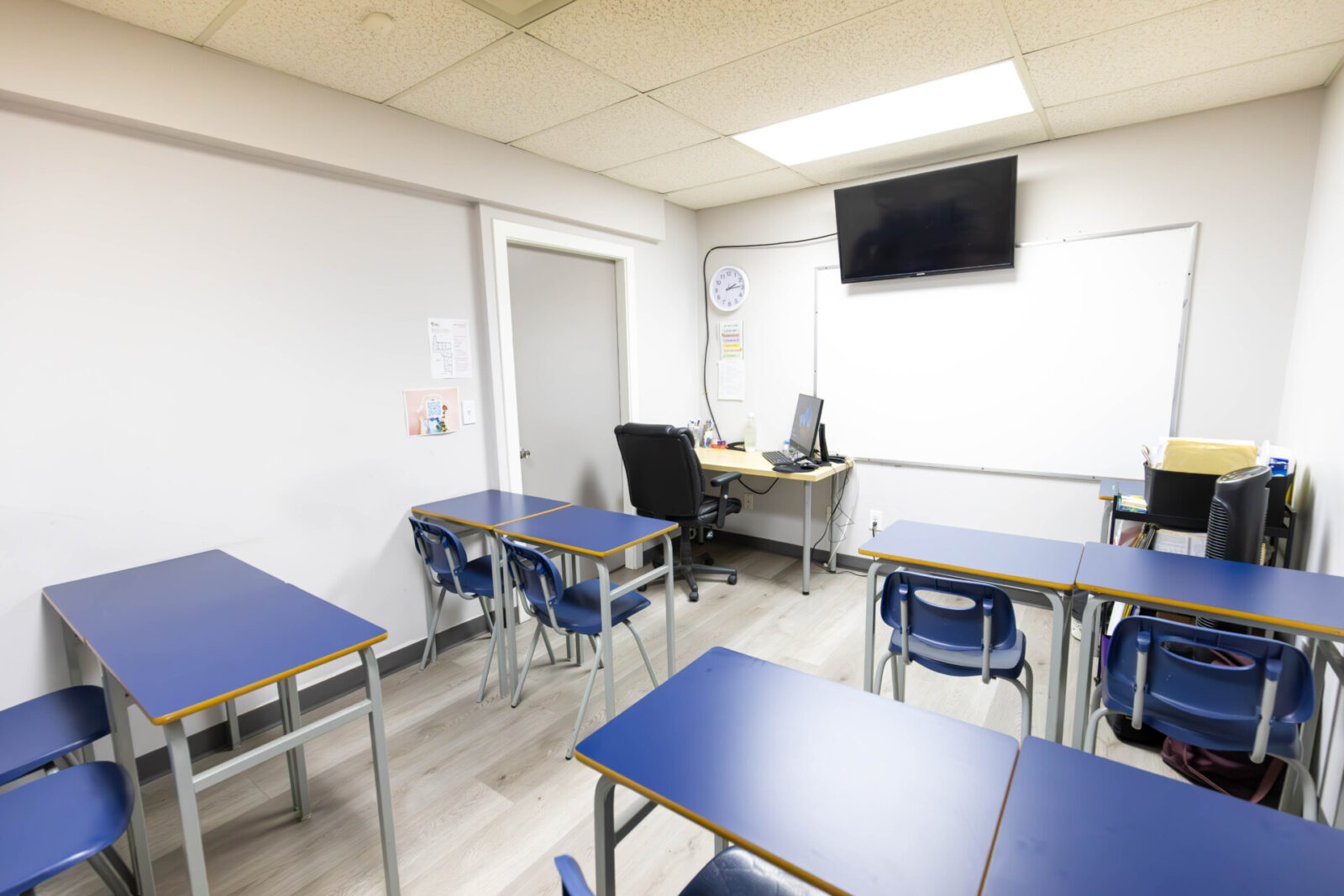Moderner Klassenraum mit blauen Tischen, Whiteboard und Lehrerarbeitsplatz in einer Sprachschule.