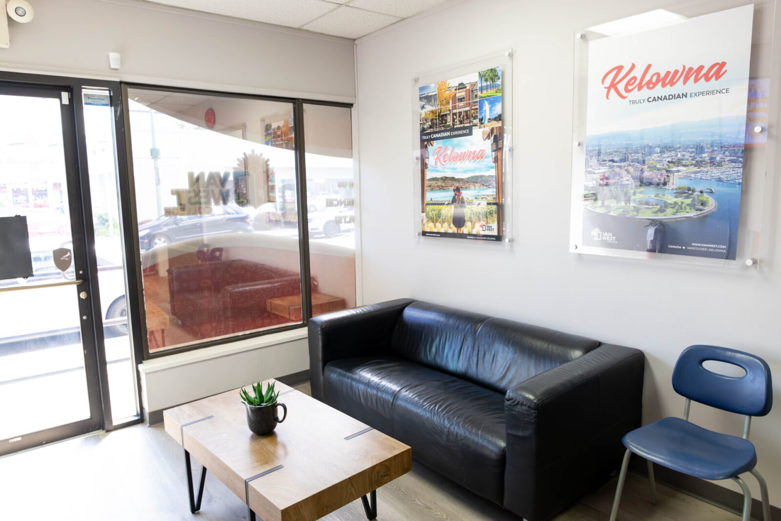 Moderne Lobby des VanWest College mit Ledersofa, Holztisch und Kelowna-Reisepostern.