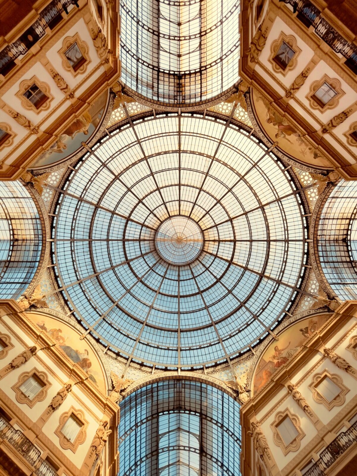 Glas- und Eisenkuppel der Galleria Vittorio Emanuele II in Mailand, mit kunstvollen Verzierungen und symmetrischer Architektur.