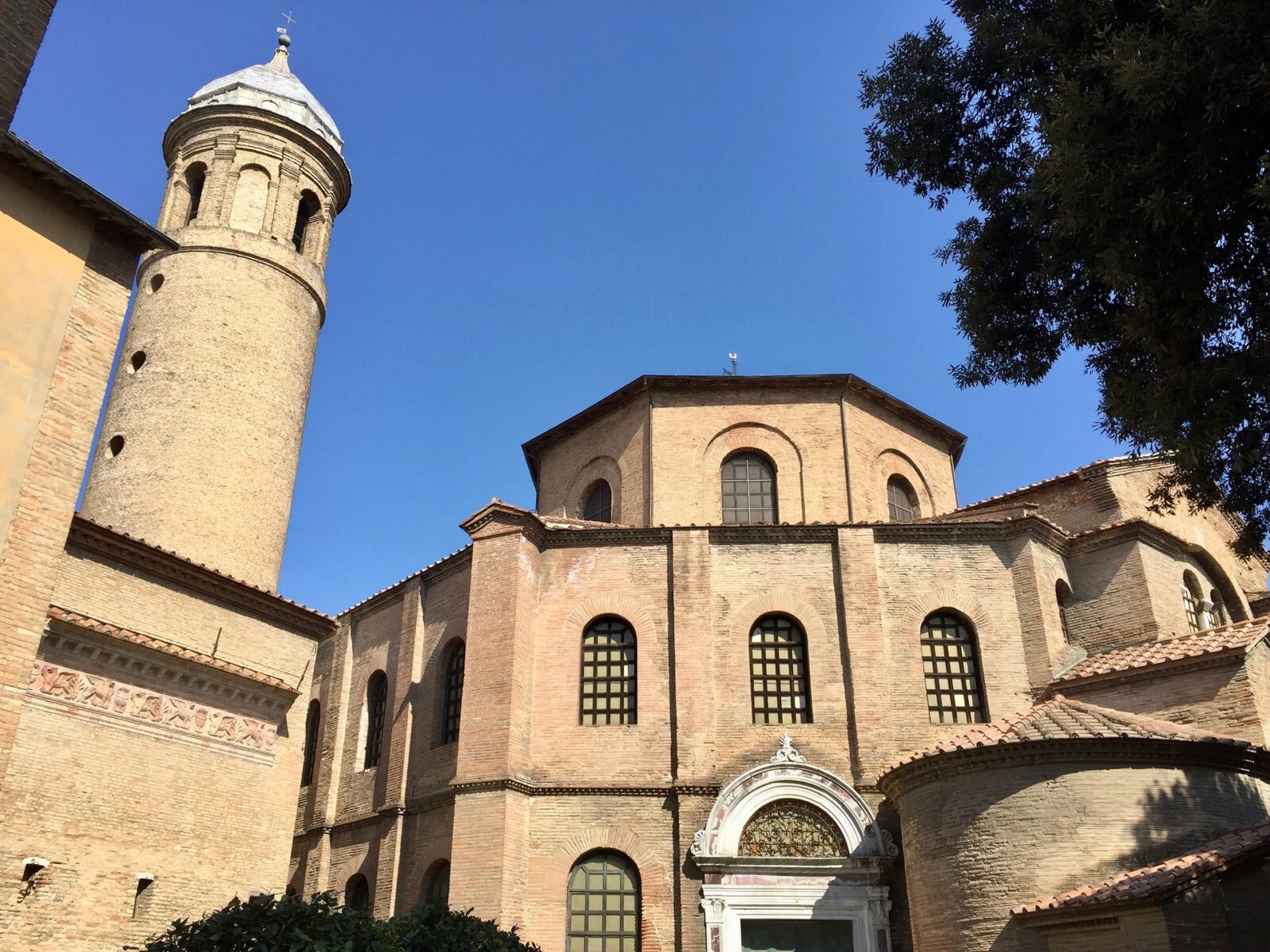 Historische Backsteinkirche mit Rundturm und markanter Architektur vor blauem Himmel.