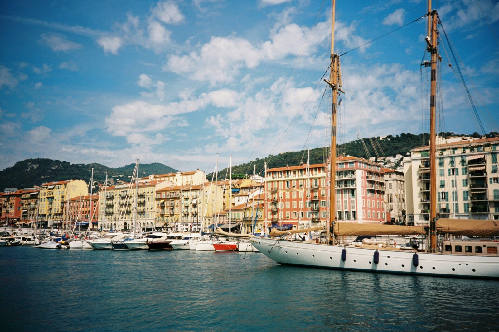 Malerischer Hafen von Nizza an der Côte d’Azur mit bunten Häusern, Segelbooten und klarem blauen Himmel.