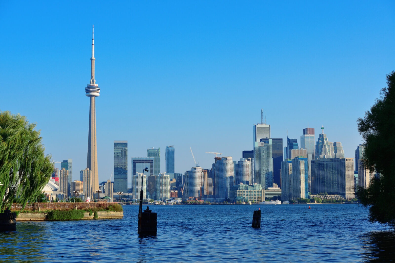 Toronto Skyline mit CN Tower und modernen Hochhäusern, aufgenommen vom Wasser aus an einem sonnigen Tag.