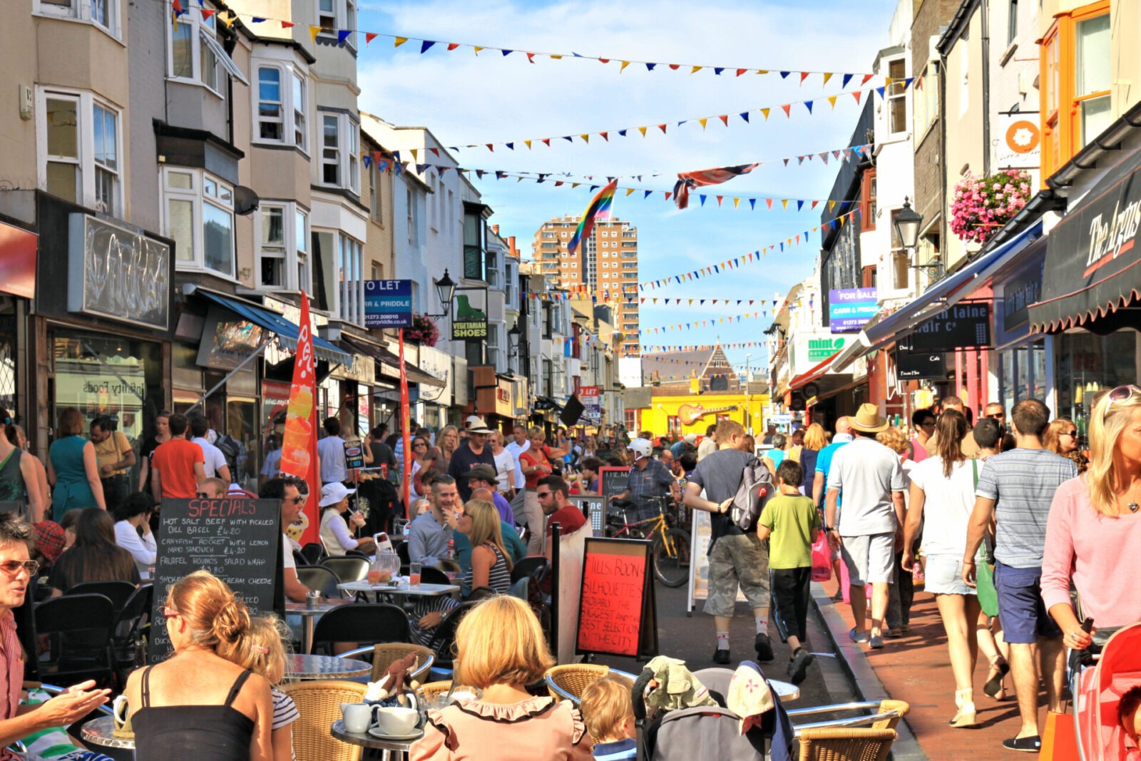 Lebendige Straßenatmosphäre in der North Laine in Brighton mit bunten Geschäften, Cafés und Menschen.