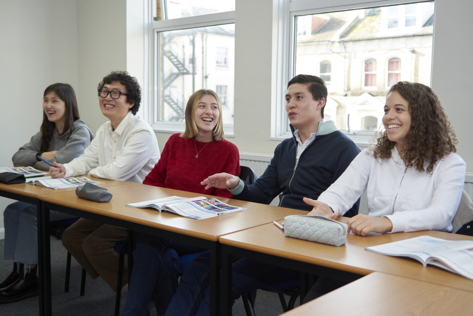 Lachende Sprachschüler in einem Klassenzimmer während einer interaktiven Unterrichtsstunde.