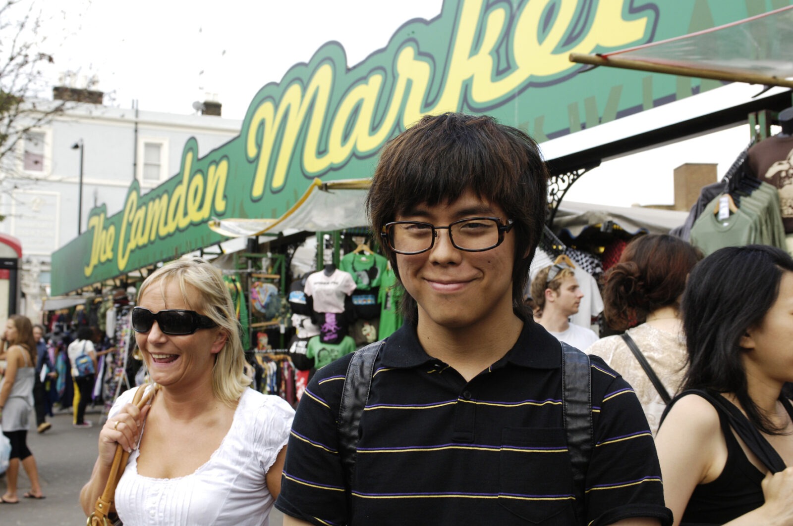 Junger Mann auf dem Camden Market in London mit fröhlicher Atmosphäre und bunten Marktständen.