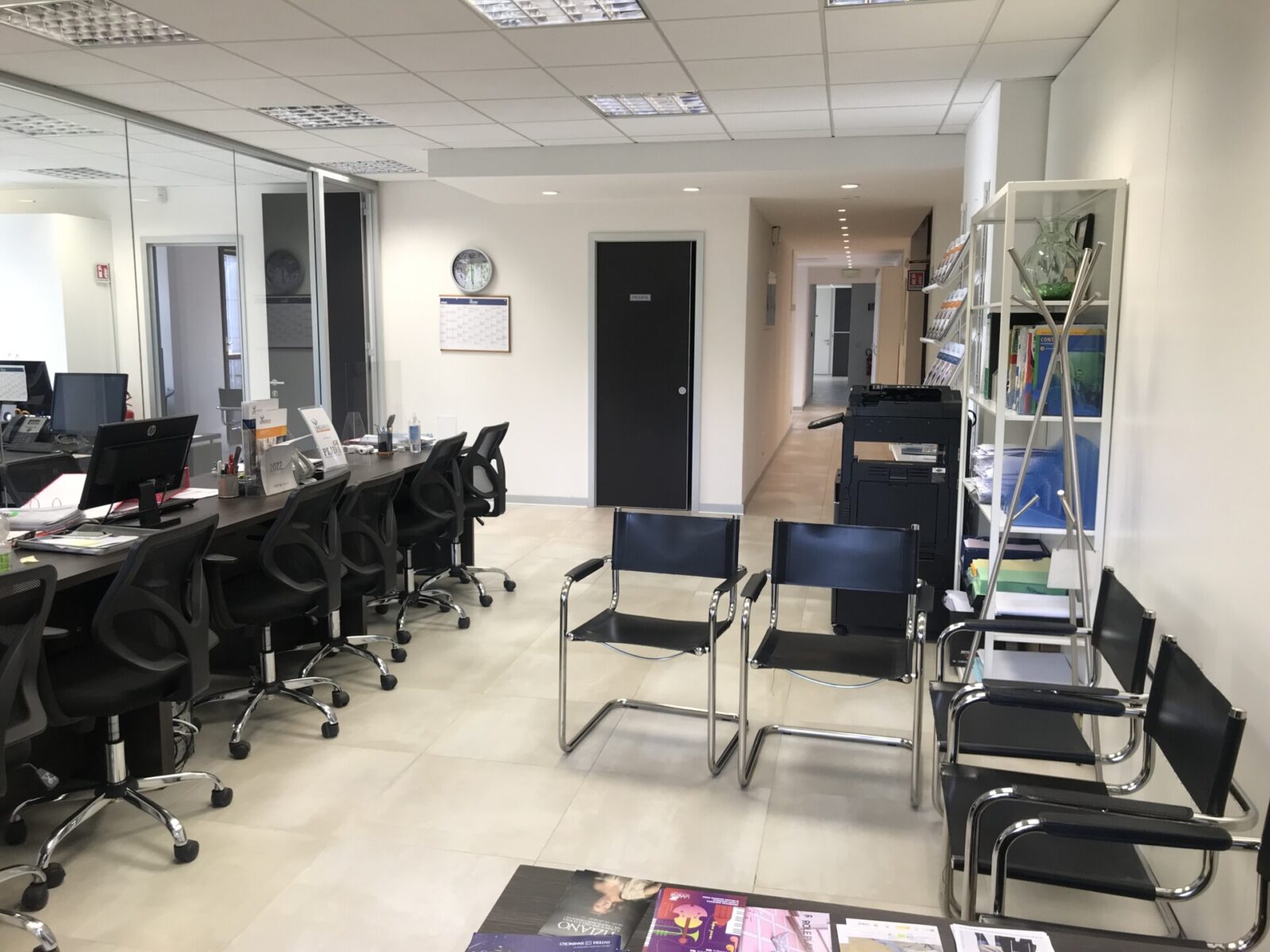 Modernes Büro mit Empfangsbereich, Wartebereich und Arbeitsplätzen mit Computern.