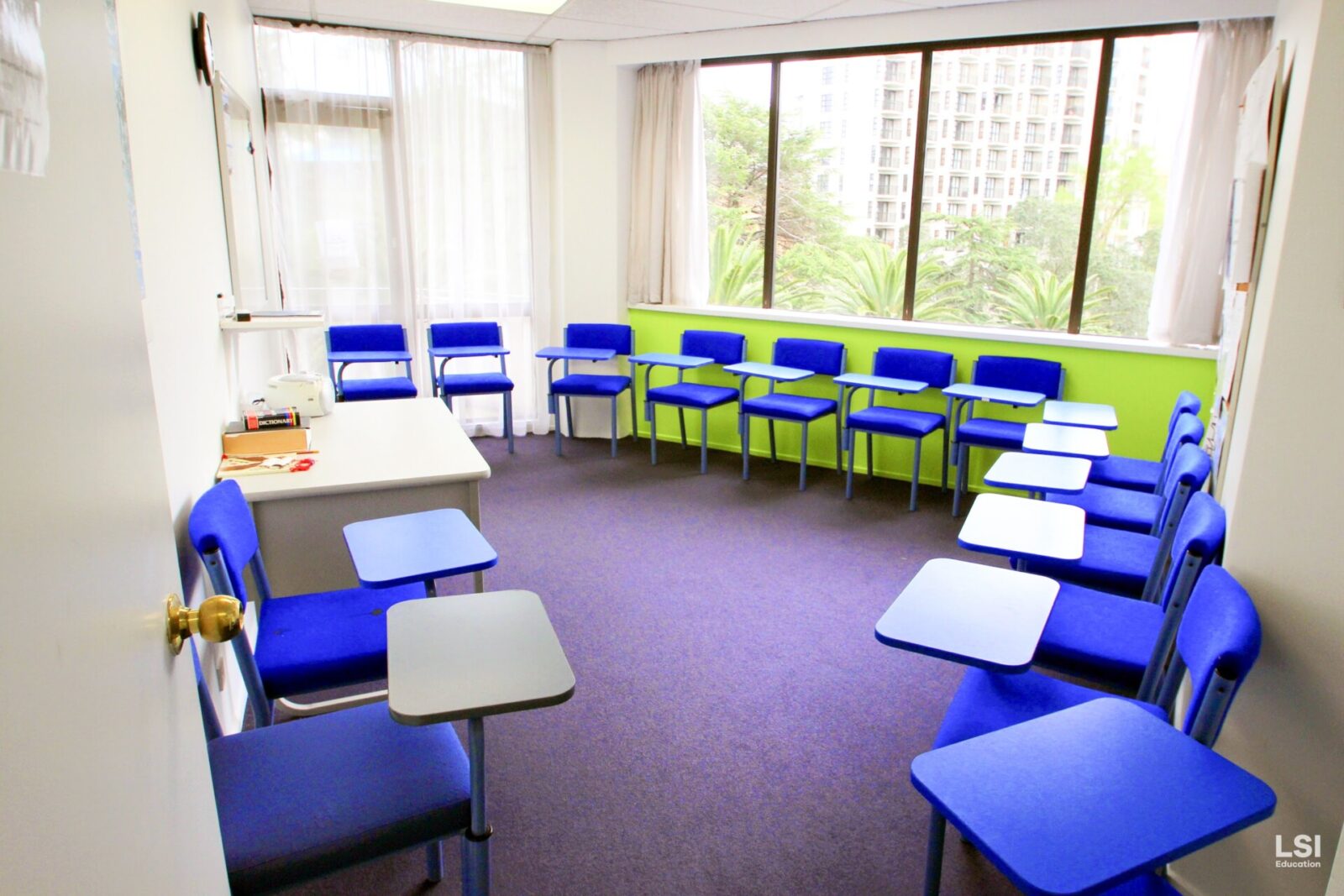 Heller und moderner Klassenraum in der LSI-Sprachschule mit blauen Stühlen und großen Fenstern.